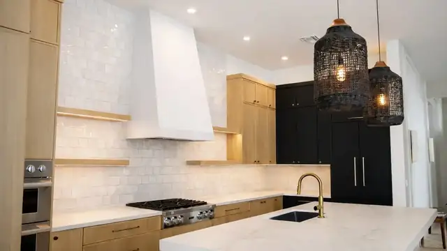 Jupiter kitchen remodel with white oak cabinets, glossy white tile, plaster range hood, black pantry wall and woven pendants