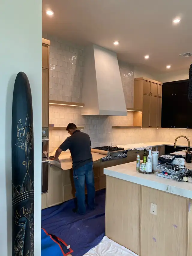 Palmhouse installer fitting a quartz counter in a white oak kitchen with the floor protected