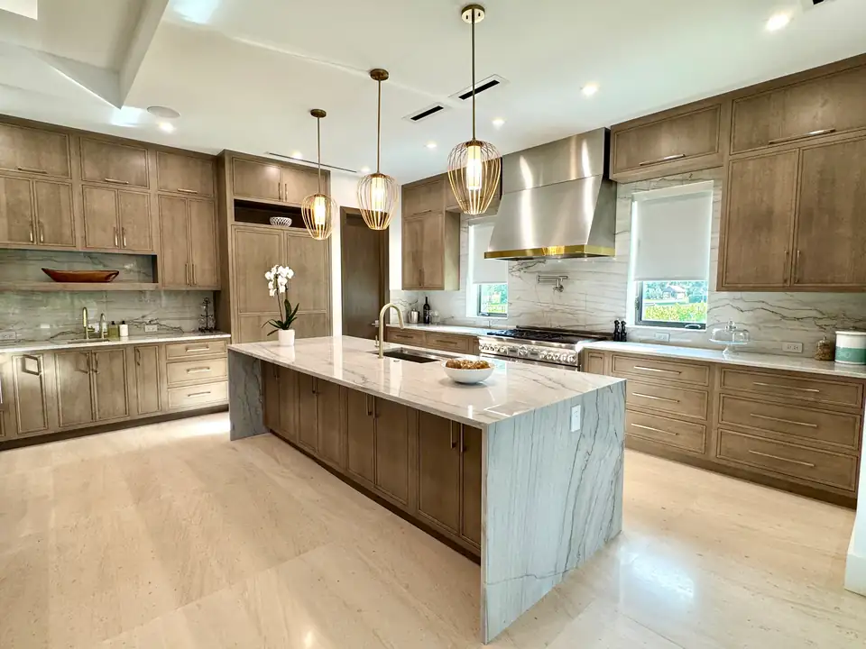 Kitchen remodeling Jupiter FL: wood shaker cabinets, quartzite waterfall island, brass pendants and stainless range hood