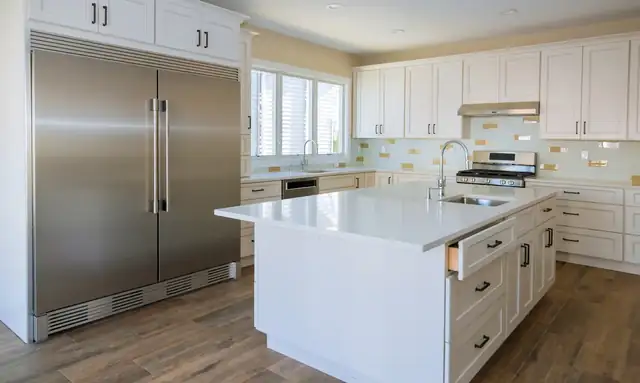 Jupiter kitchen with a white shaker island, column refrigerator and freezer and gold hardware