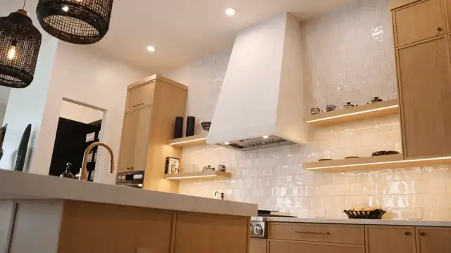 Jupiter kitchen with quartz island, brass faucet, white oak cabinets and black wicker pendants