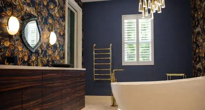 High-end bathroom renovation by Palmhouse with a freestanding soaking tub, navy walls, botanical wallpaper and brass fixtures