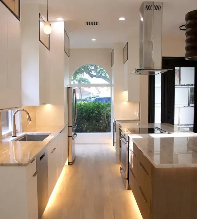 Palm Beach County kitchen with white cabinets, wood island, marble-look counters and an arched window over the sink
